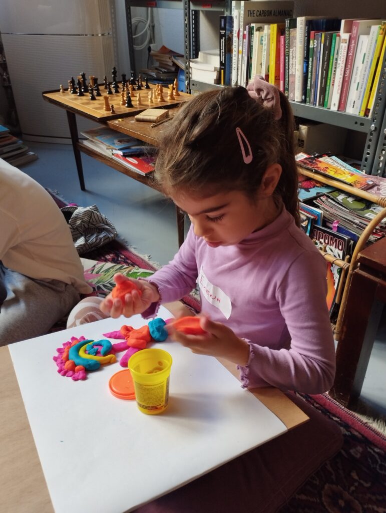 Κορίτσι φτιάχνει κατασκευές με πλαστελίνη πάνω σε χαρτ